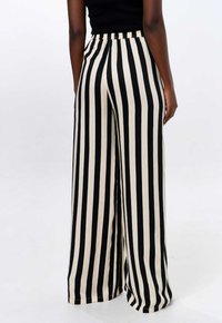 Wijdvallende broek met een zwart en crèmekleurig verticale streepdesign, elastische tailleband en een zachte, lichte stoffen textuur.