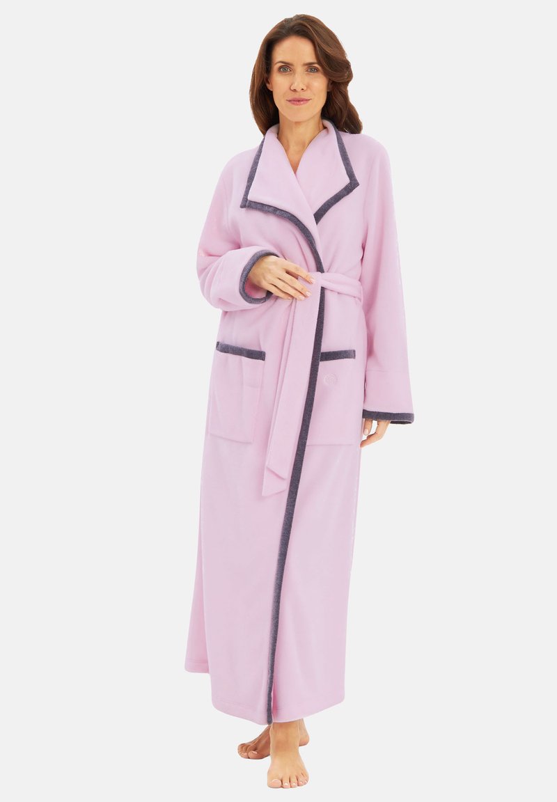 Light pink fleece bathrobe with a shawl collar, navy piping, two front pockets, and a matching belt. Full-length design and long sleeves.