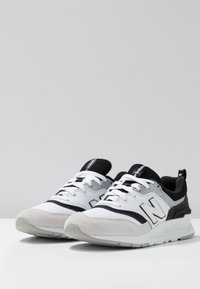 Czarno-białe trampki z cholewką z siateczki i zamszu, kontrastowymi paskami, okrągłymi sznurówkami oraz amortyzowaną podeszwą zapewniającą komfort.