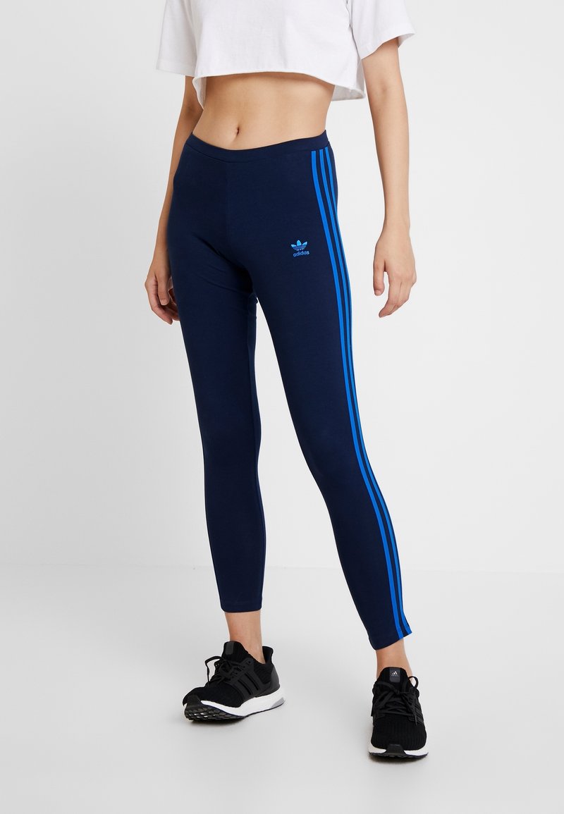 Marina leggings gjorda av stretchigt material har tre blå ränder längs sidorna och en liten blå logotyp framtill.