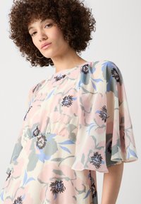 Floral midi dress featuring soft pastel colors, sheer cape sleeves, and a cinched waist. The fabric has a smooth texture with floral patterns.