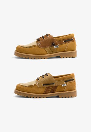 Paire de chaussures décontractées en suède beige et marron à lacets, semelles épaisses en caoutchouc, coutures visibles et petite étiquette en tissu "Caval" sur les côtés.