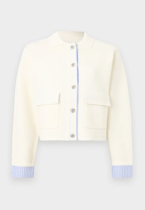 Cardigan court crème avec poignets rayés bleus, boutons floraux argentés sur le devant, deux poches à rabat et un col classique.