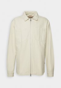 Langärmlige Jacke in cremefarben mit Kragen, Frontreißverschluss und zwei Brusttaschen, vor einem schlichten Hintergrund präsentiert.