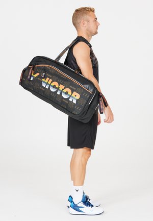 Sort sportstaske i duffel stil med orange og hvit "VICTOR"-logo, geometriske mønstre, justerbar strop og slidstærkt materiale.