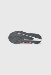 Semelle de chaussure de sport en caoutchouc gris avec un motif de bande de roulement texturé. Comprend une semelle intermédiaire blanche et des accents rouges sur les côtés.