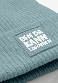 Light blue knitted beanie with a ribbed texture. Features a rectangular patch displaying "Bin Da KANN LOSGEHEN" in white bold lettering.