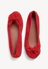 Bailarinas de ante rojo con punta redonda, decoradas con un lazo. Textura suave y color sólido. Las plantillas blandas brindan comodidad.