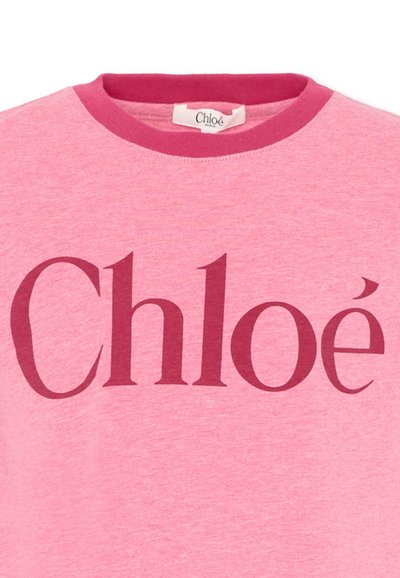 Jasnoróżowa bluza z okrągłym dekoltem, z ciemnoróżowym wykończeniem przy szyi oraz dużym ciemnoróżowym logo "Chloé" na wysokości klatki piersiowej.