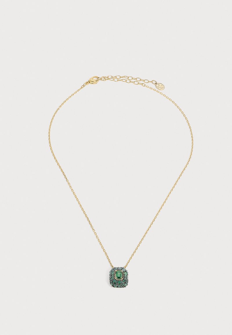Collier délicat en chaîne d’or avec un pendentif en pierre précieuse carrée vert émeraude entouré de petites pierres vertes sur fond blanc.
