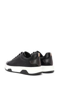 Sneaker in pelle nera con finitura testurizzata, suola bianca e dettagli a contrasto al tallone. Include una chiusura con lacci e forma arrotondata.
