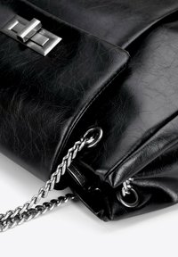 Borsa in pelle nera con finitura testurizzata, tracolla in catena argentata e chiusura metallica rettangolare sul davanti.