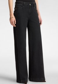 Vaqueros de denim negros de pierna ancha con una textura suave, que cuentan con bolsillos frontales, pasadores para el cinturón y un cierre de botón.