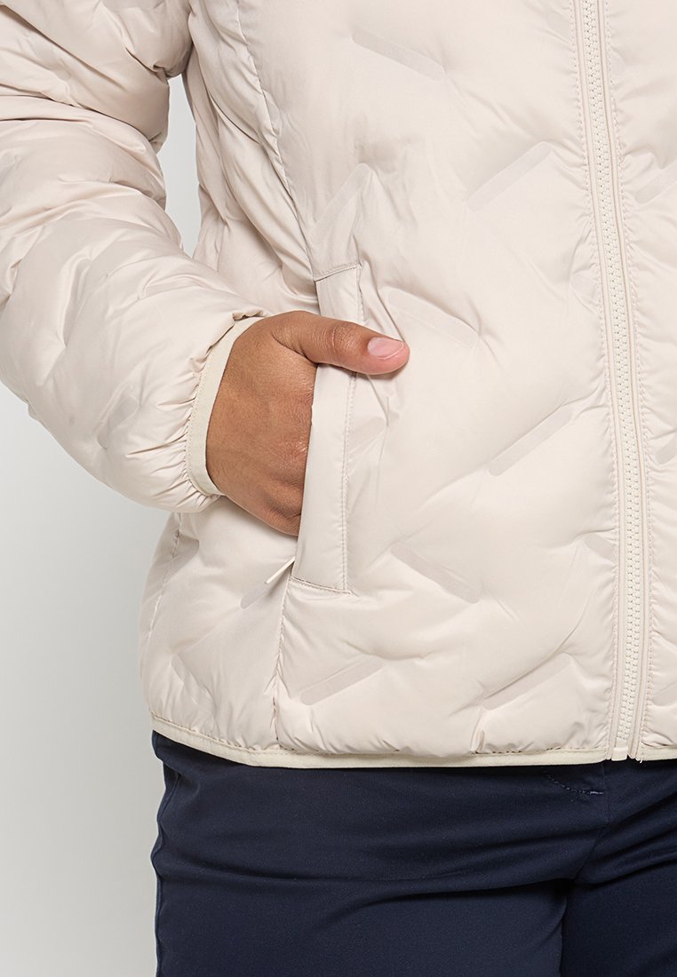 Jas beige'owa kurtka puchowa z pikowanym wzorem i elastycznymi mankietami, z boczną kieszenią i pełnym zapięciem na zamek.