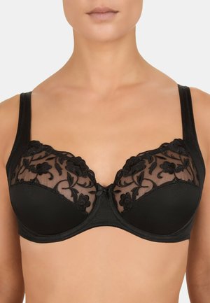 Soutien-gorge noir avec armatures et overlay en dentelle florale sur des bonnets en mesh transparent, porté par une femme visible du menton au haut du torse.