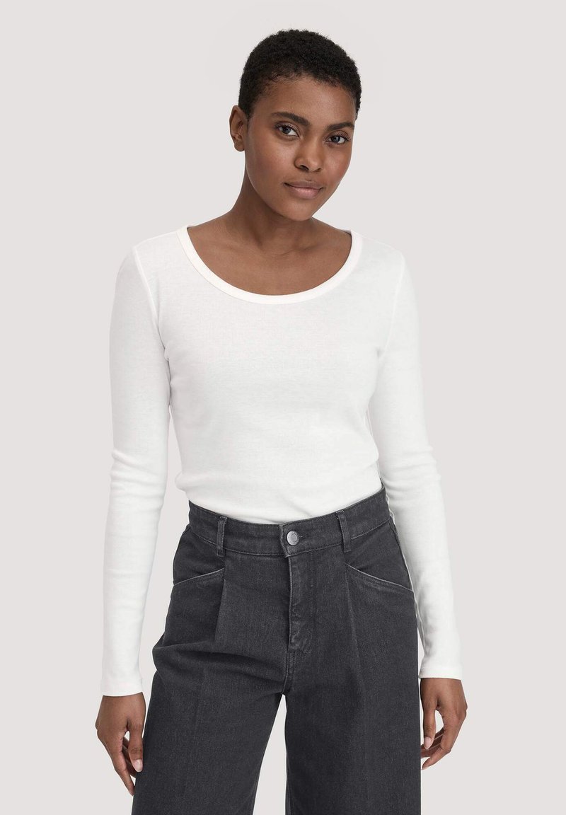 Witte lange mouwen blouse met een ronde halslijn, gecombineerd met hooggetailleerde donkere denim broek met zijzakken en een knoopsluiting.