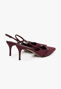 Bordowe zamszowe szpilki typu slingback z ostrymi noskami, smukłymi obcasami i krzyżującymi się paseczkami z elementami w kolorze złotym.