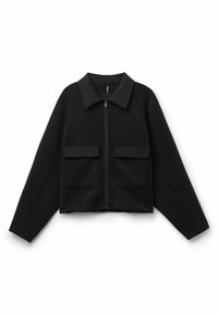 Schwarze, taillierte Jacke aus weichem Stoff, mit einem Kragen, einem Reißverschluss auf der Vorderseite und zwei großen aufgesetzten Taschen auf der Brust.