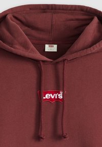 Burgunderfarbener Hoodie aus weichem Material, mit einem roten gestickten Levi's-Logo und verstellbaren Kordeln an der Kapuze.