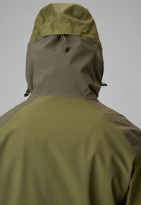 Vue arrière d'une veste à capuche vert olive avec cordons réglables sur la capuche sur un fond gris uni.