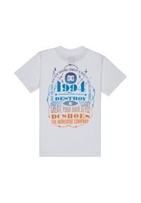 T-shirt en coton blanc avec un texte graphique bleu et orange, "DC 1994", et des éléments décoratifs. Manches courtes et col rond.
