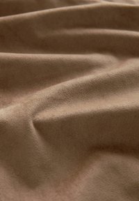Tissu en daim brun avec une texture douce, présentant des plis et des vagues délicates, mettant en valeur une surface lisse et des tons de couleurs discrets.
