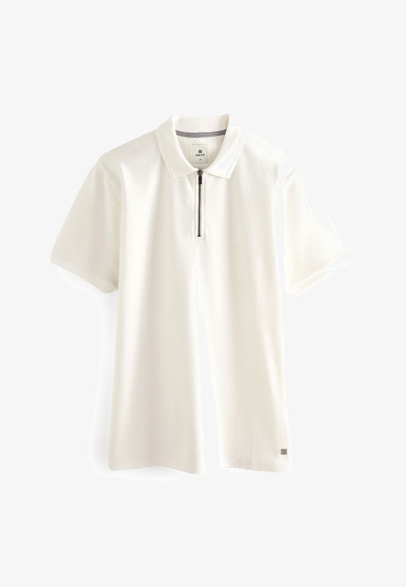 Hvid polo skjorte med lynlås i kraven, korte ærmer og tekstureret stof. Har et lille logo på nederste venstre side.