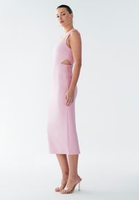 Eng anliegendes pinkfarbenes Kleid mit mittellanger Schnitt, das seitliche Cut-out-Details und breite Schulterträger aufweist. Glatte Textur, minimalistisches Design.