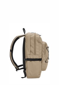 Sac à dos beige avec plusieurs compartiments zippés, bretelles réglables noires et une section de rangement avant avec cordon élastique.