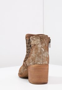 Brązowe botki sięgające kostki, o teksturowanym metalicznym wykończeniu, z plecionym detalem po bokach i słupkowym, drewnianym obcasem. Zamek błyskawiczny z tyłu.