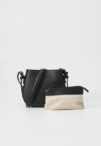 Borsa a tracolla in pelle nera con una forma strutturata e tracolla regolabile, accompagnata da una piccola pochette zip beige e nera con motivo a spina di pesce.