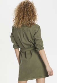 Olivově zelené, košilové šaty s páskem, s ohnutými rukávy, detailem na zadním dílu a rovný střih, vyrobené z měkké, texturované tkaniny.