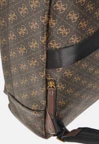 Zaino marrone con motivo, realizzato in materiale sintetico, caratterizzato da un design trapuntato, hardware dorato e spallacci in tessuto nero.