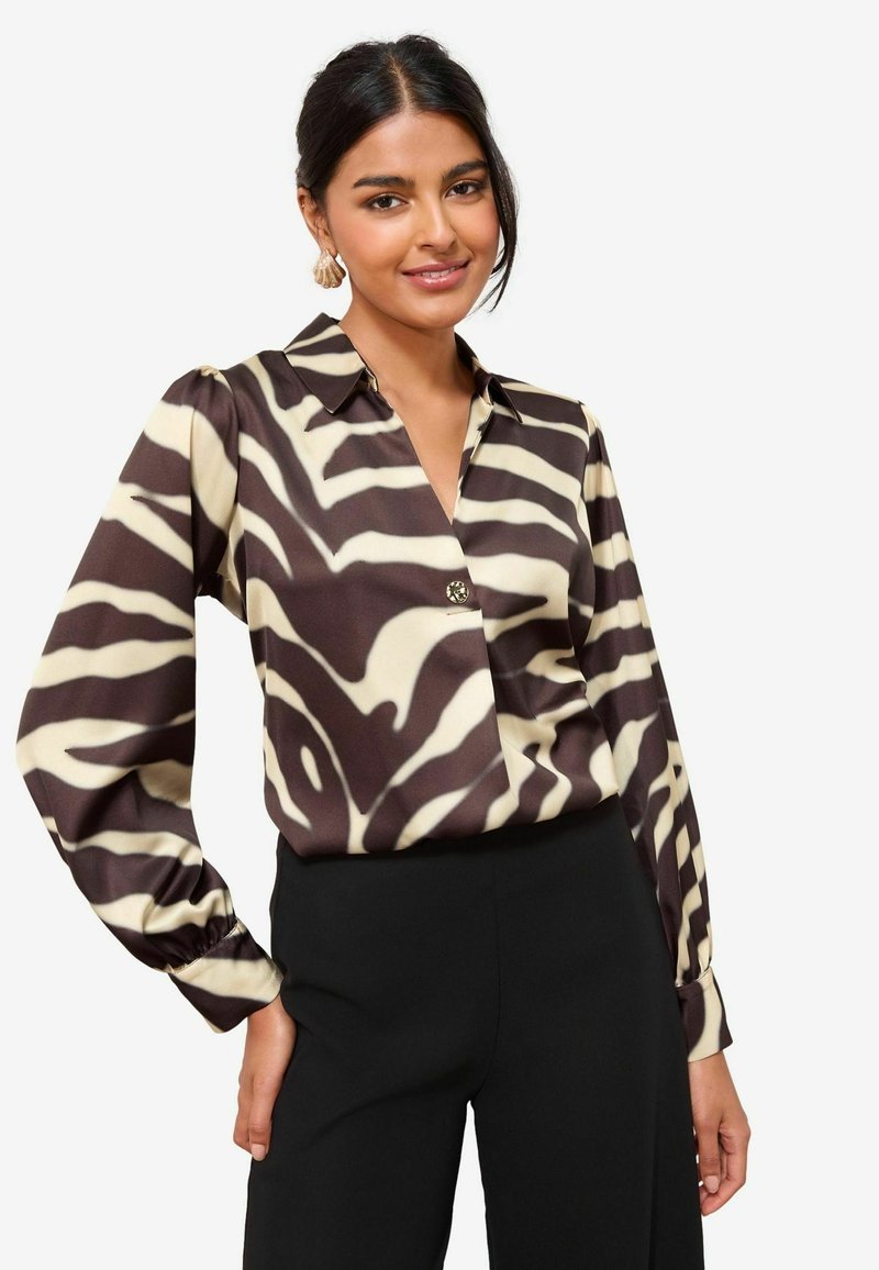 Pruun ja kreemjas zebra-mustriga pluus, millel on krae, pikad varrukad ja esiservas nööpide detail. Kerge kangas, millel on sile tekstuur.