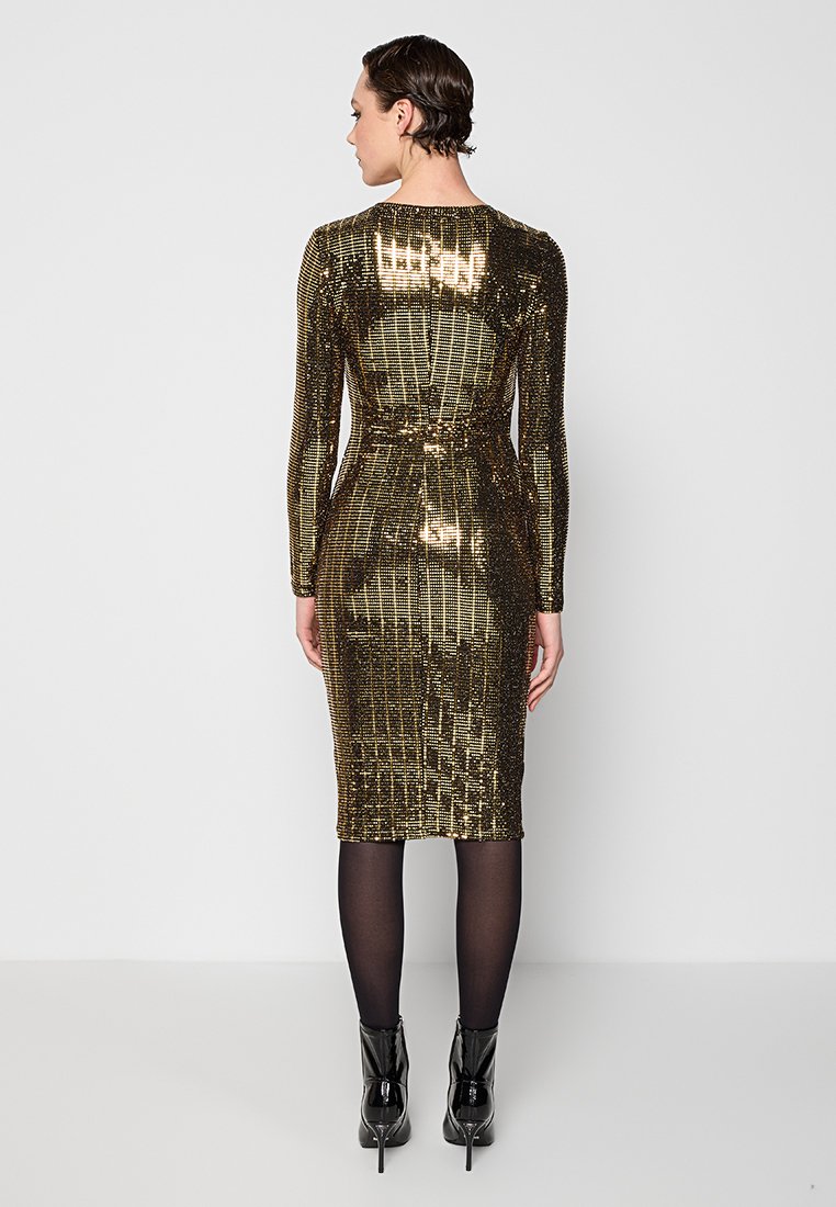Vestido midi de lentejuelas doradas con mangas largas, silueta ajustada y detalle de costura en la parte posterior, combinado con botines negros de tacón.