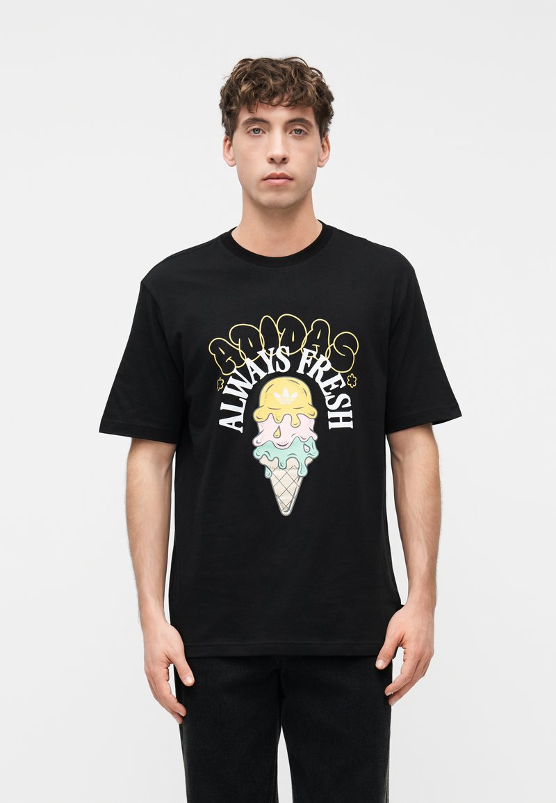 Νεαρός άνδρας που φοράει μαύρο T-shirt με πολύχρωμο λιωμένο παγωτό σε χωνάκι και το κείμενο "Adidas Always Fresh" στο μπροστινό μέρος.