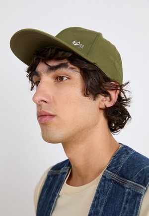 Olivengrønn baseball caps med flat brem, laget av stoff med en teksturert overflate, og med en sølvfarget logo på frontpanelet.