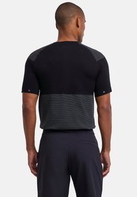 Chemise noire à manches courtes présentant un motif à rayures horizontales sur la moitié inférieure et des accents texturés sur les épaules.