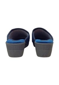 Scarpe slip-on in suede blu con suole in gomma grigia e texture rigata. La vista posteriore mostra il tallone arrotondato e l'interno imbottito.