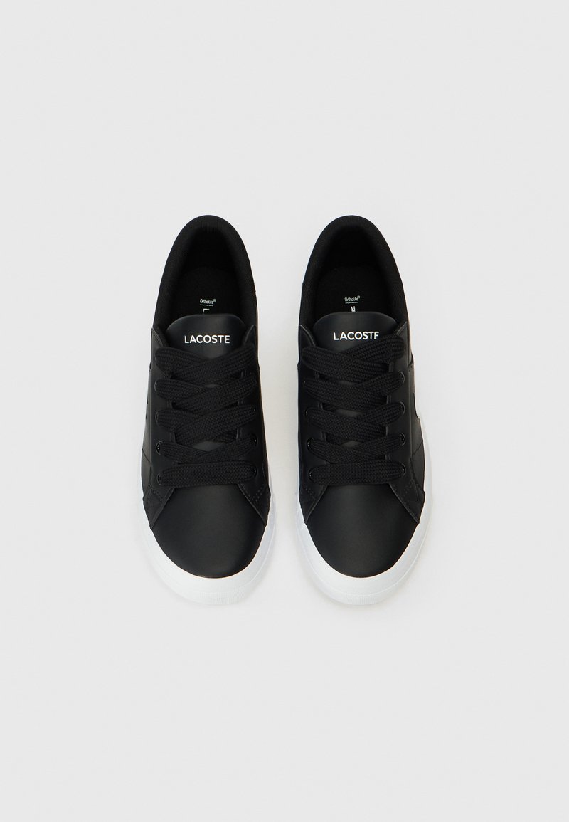 Sneaker nere con tomaia in pelle liscia, punta rotonda e suola in gomma bianca. Presentano lacci neri e il marchio 'Lacoste' sulla linguetta.