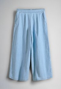 Pantaloni din denim albastru deschis, cu croiala largă și lungime scurtă, cu talie elastică și buzunare laterale, atârnați pe un fundal bej.