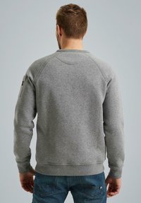 Grauer Sweatshirt mit Rundhalsausschnitt und gerippten Bündchen, verfügt über Raglanärmel und ein kleines Stoffpatch am linken Arm. Weicher Stoff.