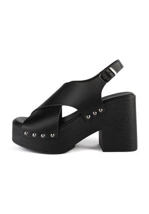 Crne platforme sandale s dizajnom križnog remena, izrađene od glatke kože, s metalnim zakovicama duž đona i podesivim remenom s kopčom.