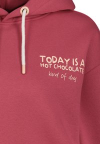 Katoenen hoodie in het roze. Heeft een trekkoordkap en een voorzijde met de tekst "VANDAAG IS HET EEN WARME CHOCOLADE-dag" in crème.