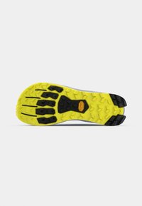 Semelle de chaussure avec une base jaune vif, ornée de motifs de traction en caoutchouc noir et d'une surface texturée. La semelle extérieure comporte un logo Vibram.