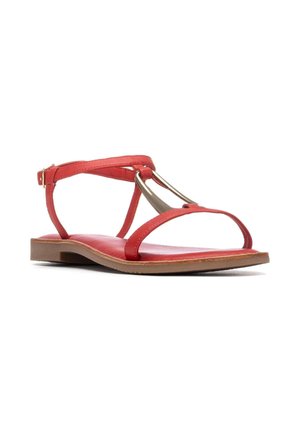Sandalia roja con suela plana, con tiras delgadas y un adorno metálico. La parte superior es lisa y la plantilla está acolchada para mayor comodidad.