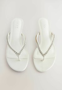 Bílé žabky s hladkým povrchem, se strapcem ve tvaru V zdobeným průhlednými, třpytivými kamínky. Jednoduchý a elegantní design.