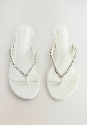 Bela japonka z gladko teksturo, z V-oblikovanim trakom okrašenim s prozornimi, sijočimi kamni. Preprost in eleganten dizajn.