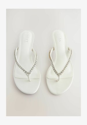 Bela japonka z gladko teksturo, z V-oblikovanim trakom okrašenim s prozornimi, sijočimi kamni. Preprost in eleganten dizajn.