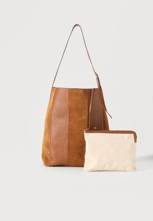 Sac d'épaule en cuir et daim marron avec une pochette zippée couleur crème placée devant sur fond blanc uni.